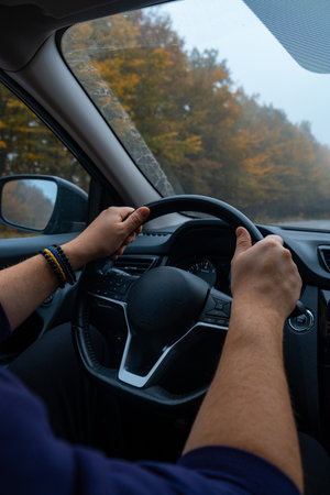 Person Driving by the road at foggy autumn highway