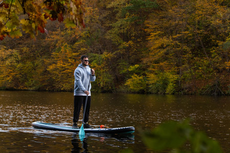 Man Paddleboarding in Autumn Lakeの写真素材