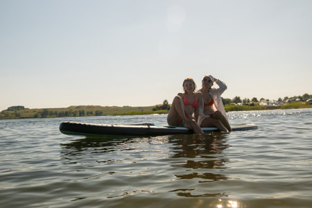 Women Enjoying Paddleboarding on a Sunny Dayの写真素材