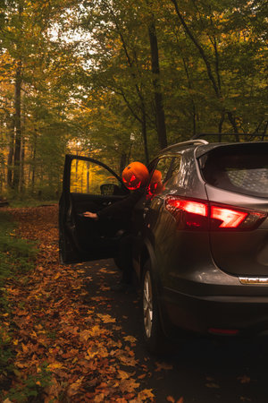 Autumn SUV with Driver with Pumpkin Head in Forest
