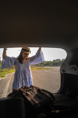 Smiling Woman with Backpack by Car on Scenic Roadの写真素材