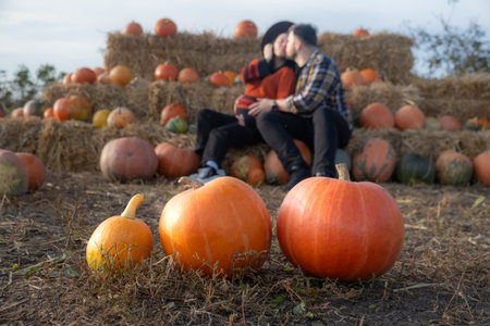 Couple sitting on hay bales in a pumpkin patchの写真素材