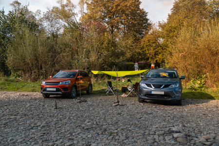 Camping Setup by the Riverbank with Carsの写真素材
