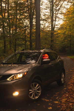 Autumn SUV with Driver with Pumpkin Head in Forestの写真素材