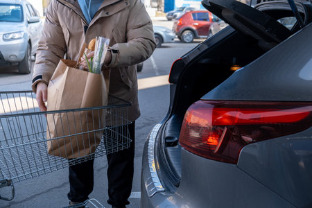 Man Loading Groceries into Car Trunk