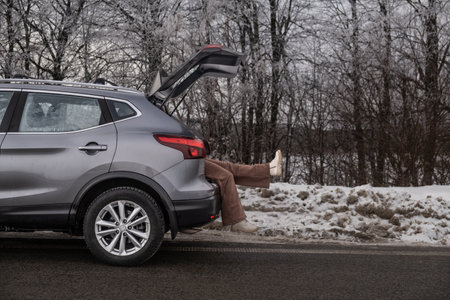 Person sitting in SUV trunk on snowy roadside