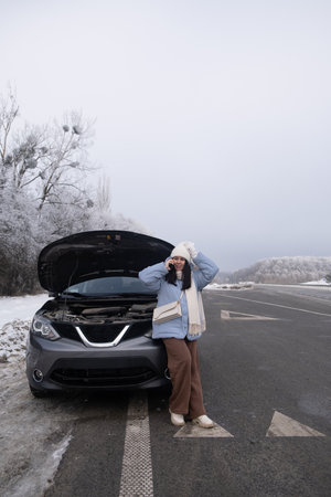 Woman watching at Car Engine on Snowy Roadsideの写真素材