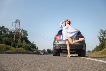 Cheerful Woman Posing by SUV on Sunny Dayの写真素材