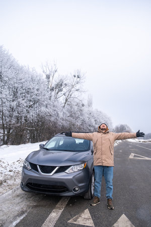 Person with SUV on Snowy Road in Winter Landscapeの写真素材