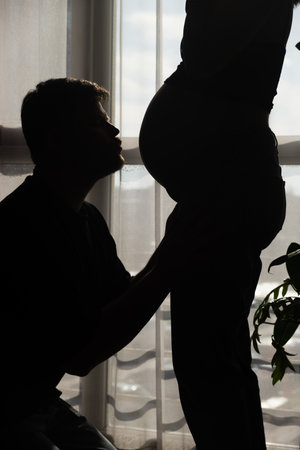 Intimate Moment of Expecting Parents by the Windowの写真素材