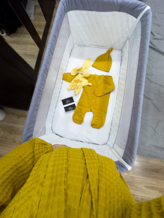 Cozy Baby Crib with Yellow Outfit and Accessoriesの写真素材