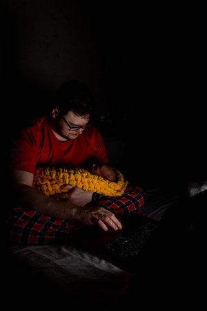 Father Holding Baby While Using Laptop in Dim Lightの写真素材