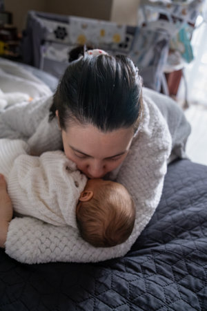 Mother Kissing Baby in Cozy Bedroom