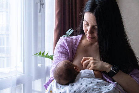 Mother Breastfeeding Baby by Windowの写真素材
