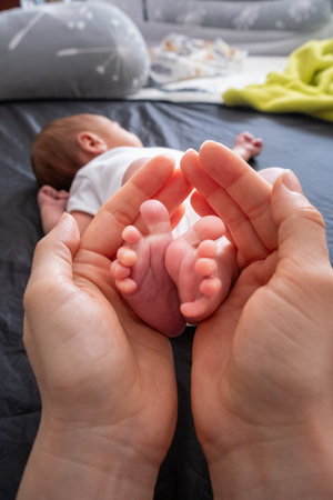 Tender Moment: Adult Hands Holding Newborn Baby Feetの写真素材