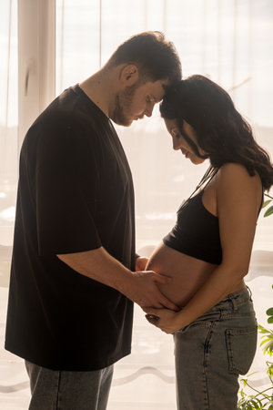 Intimate Moment of Expecting Parents by the Windowの写真素材