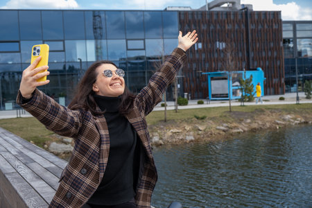 Woman Taking Selfie by Modern Building and Pondの写真素材