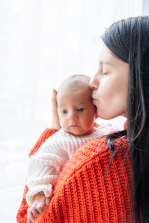 Tender Moment Between Mother and Baby by the Windowの写真素材