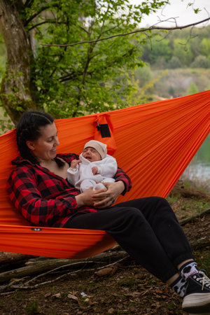 Mother and Baby Relaxing in Hammock Outdoorsの写真素材