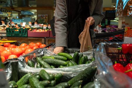 Person Selecting Cucumbers in Grocery Storeの写真素材