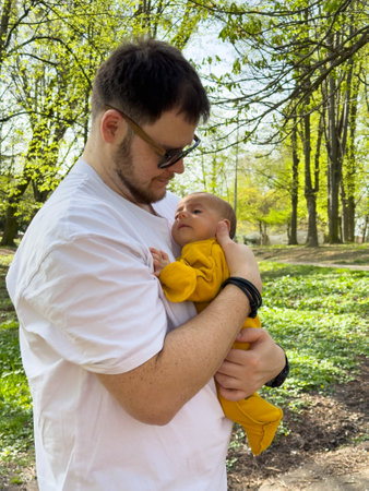 Man Holding Baby in Yellow Outfit Outdoorsの写真素材