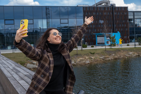 Woman Taking Selfie by Modern Building and Pondの写真素材