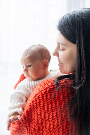 Tender Moment Between Mother and Baby by the Windowの写真素材