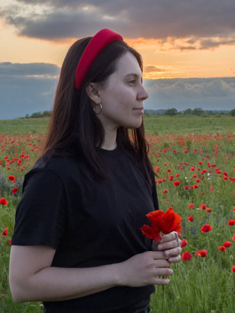 Young Woman in Poppy Field with Red Hatの写真素材