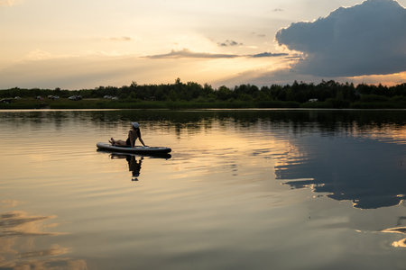 Woman Relaxing on Paddleboard at Sunsetの写真素材