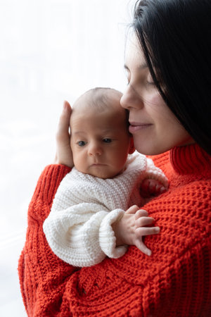 Tender Moment Between Mother and Baby by the Windowの写真素材