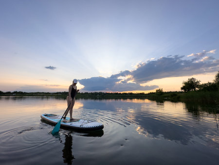 Paddleboarding at Sunset on a Tranquil Lakeの写真素材