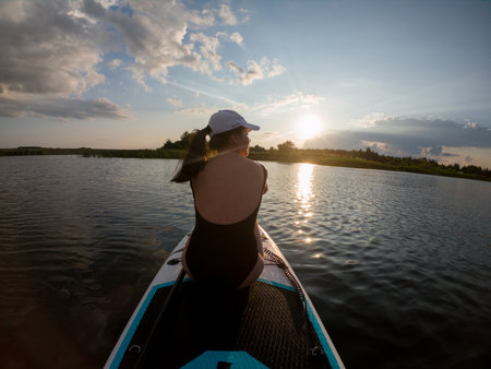 Woman Relaxing on Paddleboard at Sunsetの写真素材