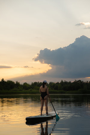 Paddleboarding at Sunset on a Tranquil Lakeの写真素材