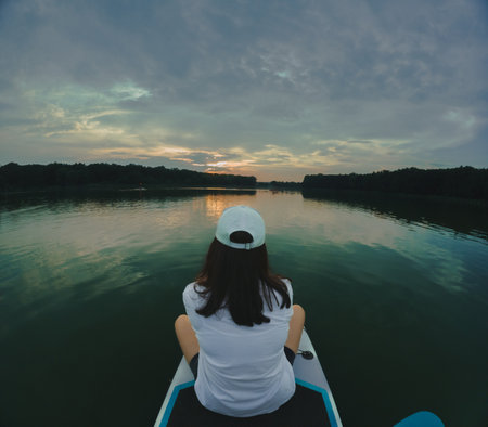 Paddleboarding at Sunset on a Calm Lakeの写真素材