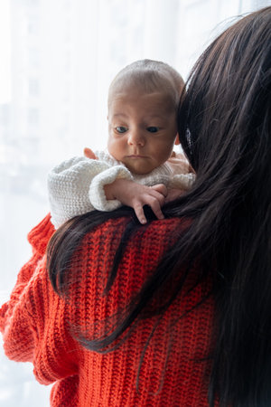 Tender Moment Between Mother and Baby by the Windowの写真素材