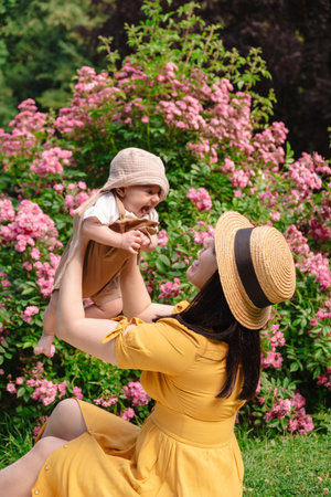 Joyful Mother and Baby in Blooming Gardenの写真素材