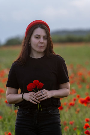 Young Woman in Poppy Field with Red Hatの写真素材