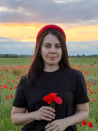 Young Woman in Poppy Field with Red Hatの写真素材