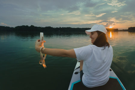 Woman Taking Selfie on Paddleboard at Sunsetの写真素材