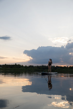 Paddleboarding at Sunset on a Tranquil Lakeの写真素材