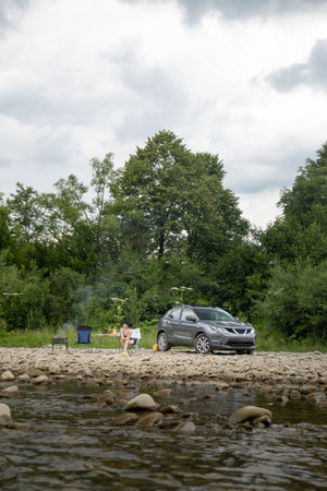 Camping by the River with SUV and Campfireの写真素材