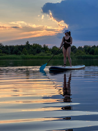 Paddleboarding at Sunset on a Tranquil Lakeの写真素材