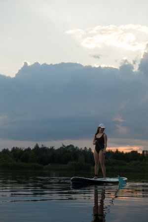 Paddleboarding at Sunset on a Tranquil Lakeの写真素材