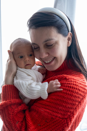 Tender Moment Between Mother and Baby by the Windowの写真素材