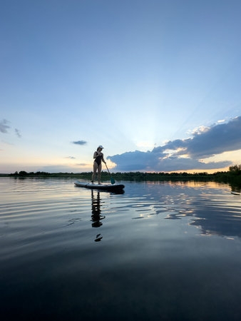 Paddleboarding at Sunset on a Tranquil Lakeの写真素材