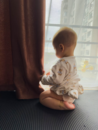 Baby in Pajamas Looking Out the Window