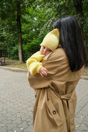 Mother Holding Baby in Yellow Outfit at Park