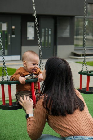 Mother and Baby on Swing in Playgroundの写真素材