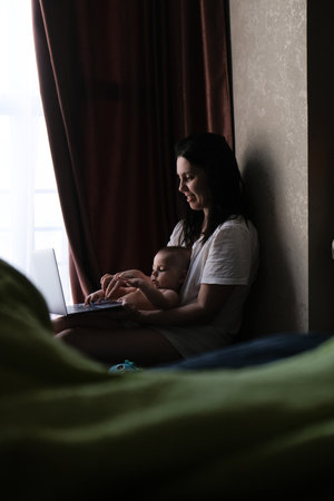Mother and Baby Using Laptop by Windowの写真素材