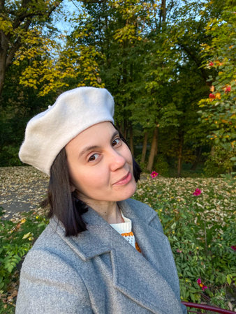 Woman in Gray Coat and Beret Smiling in Autumn Parkの写真素材